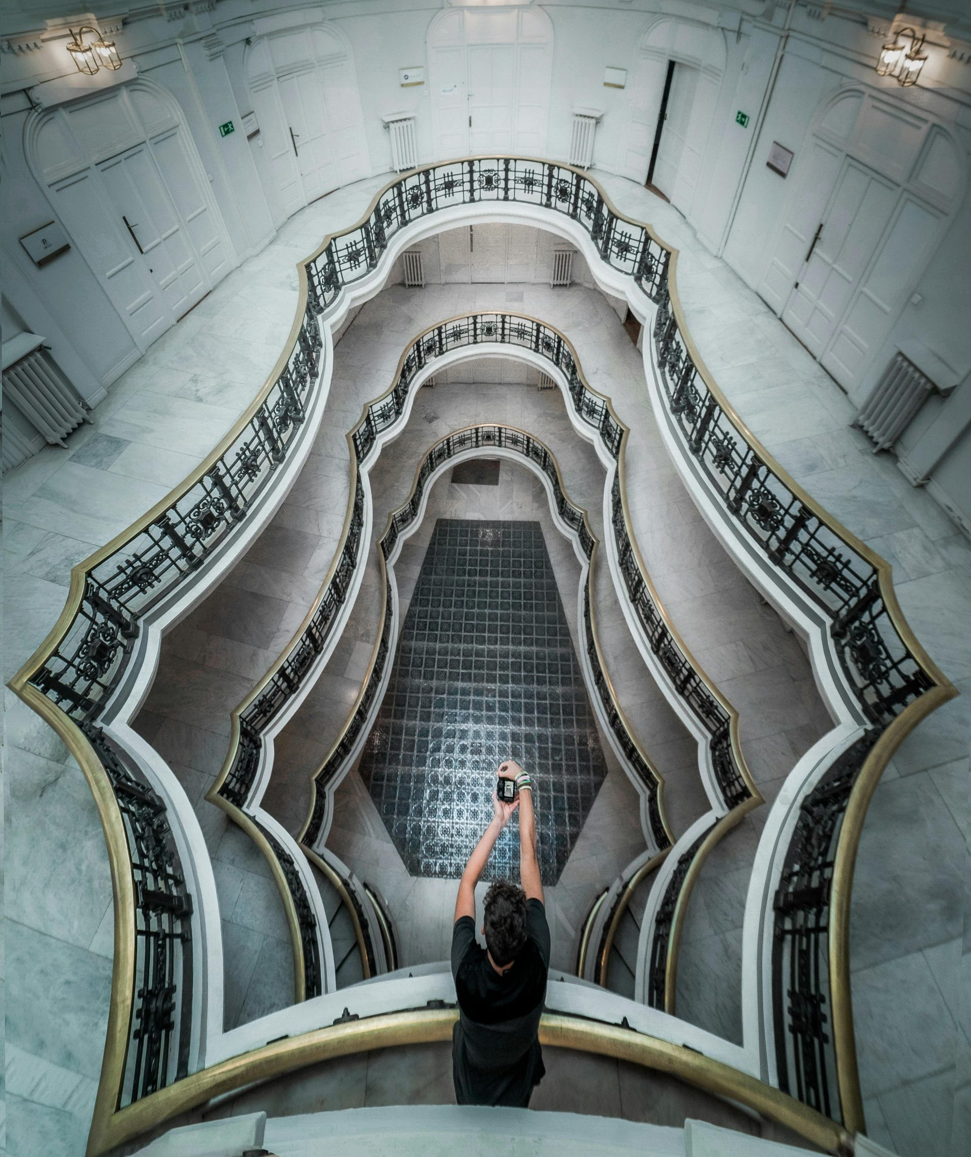 A man captures the intricate design of a luxurious spiral staircase from above.